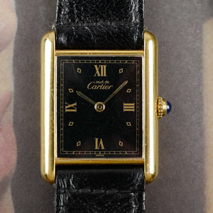 Café noir les montres Cartier Must Tank grand modèle noir 1990